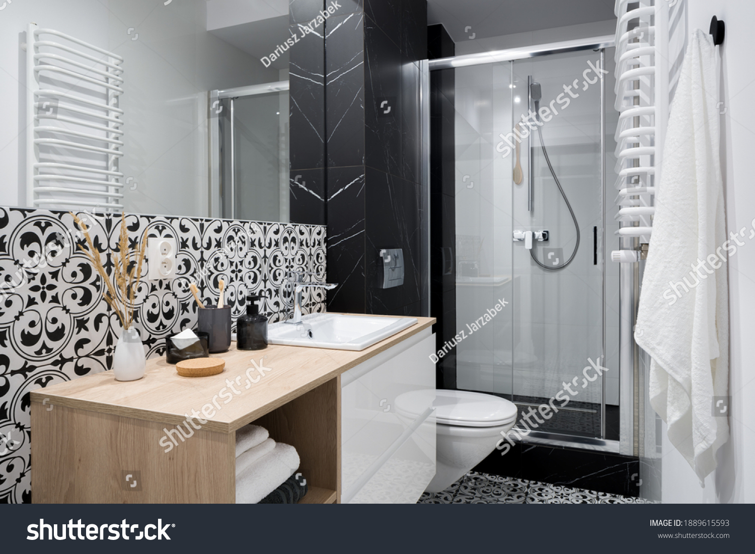 Stylish and small bathroom with decorative wall and floor tiles, big mirror and shower behind glass sliding doors #1889615593
