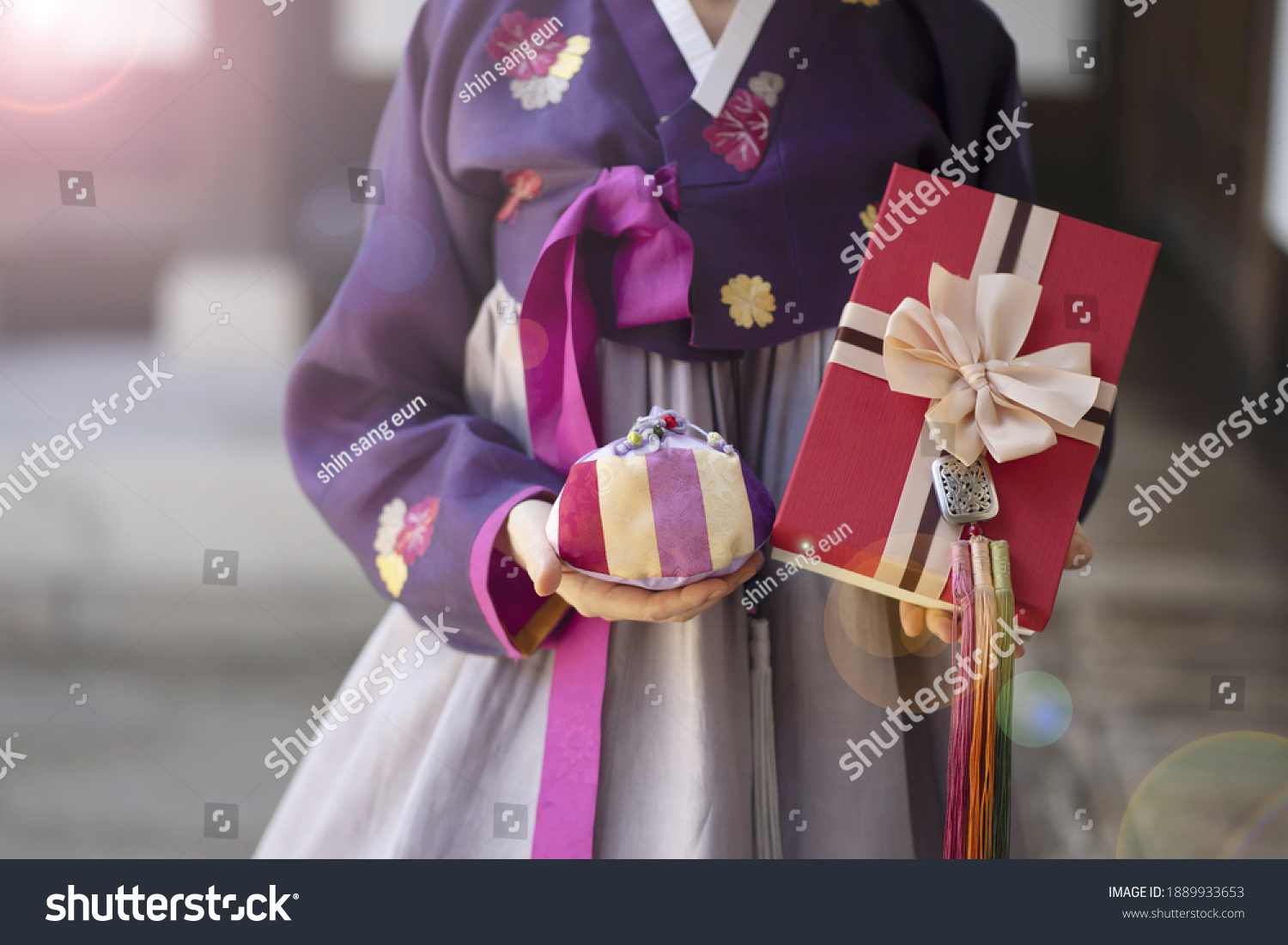 Woman in Korean traditional dress holding lucky bag with gift box
 #1889933653