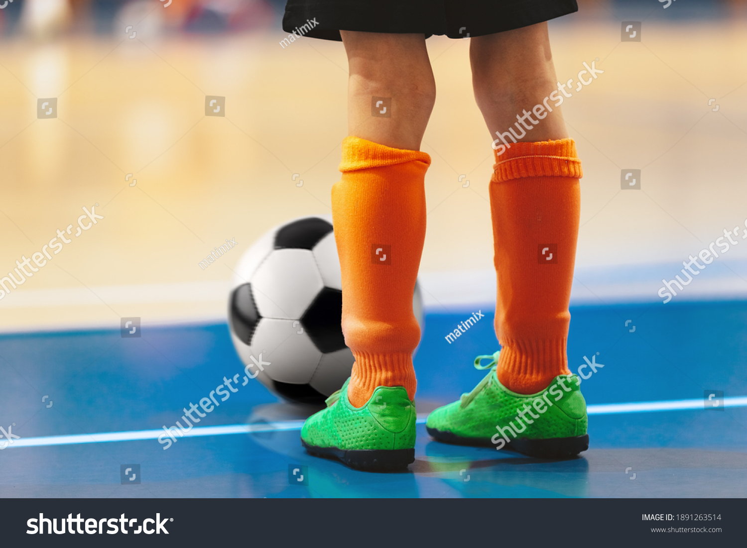 Futsal training for youth team. Young boy with soccer ball standing on white line. Indoor football soccer school practice. Kid in sportswear, black shorts, soccer cleats and orange socks #1891263514