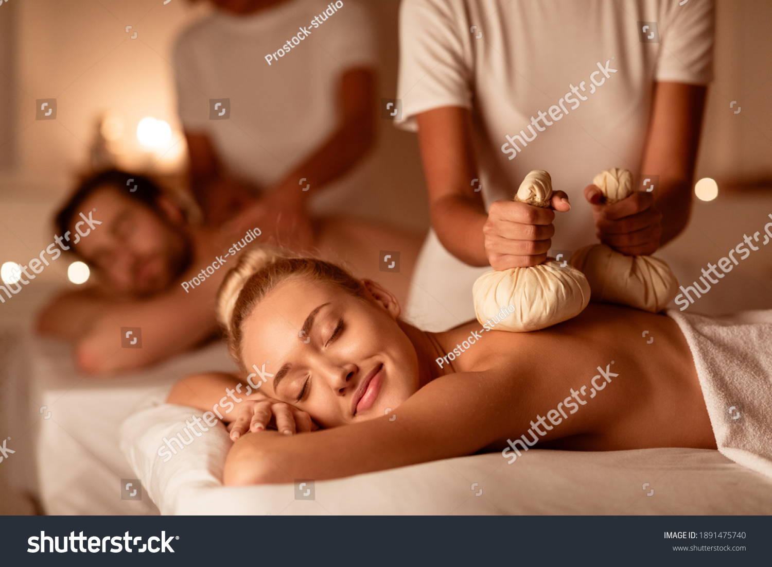 Couple Enjoying Herbal Massage. Relaxed Husband And Wife At Exotic Spa Resort, Lying With Eyes Closed Receiving Thai Massage With Aromatic Bags. Body Beauty Treatment, Relaxation And Wellness #1891475740