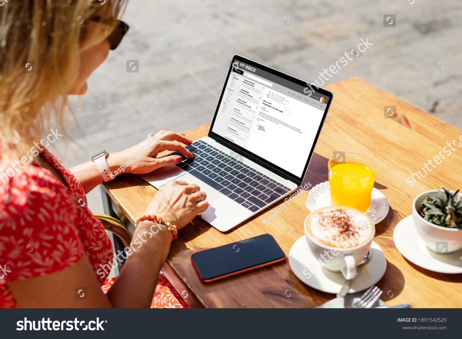 Woman reading emails on laptop at cafe. Names and all contents on screen are completely made up. #1891542529