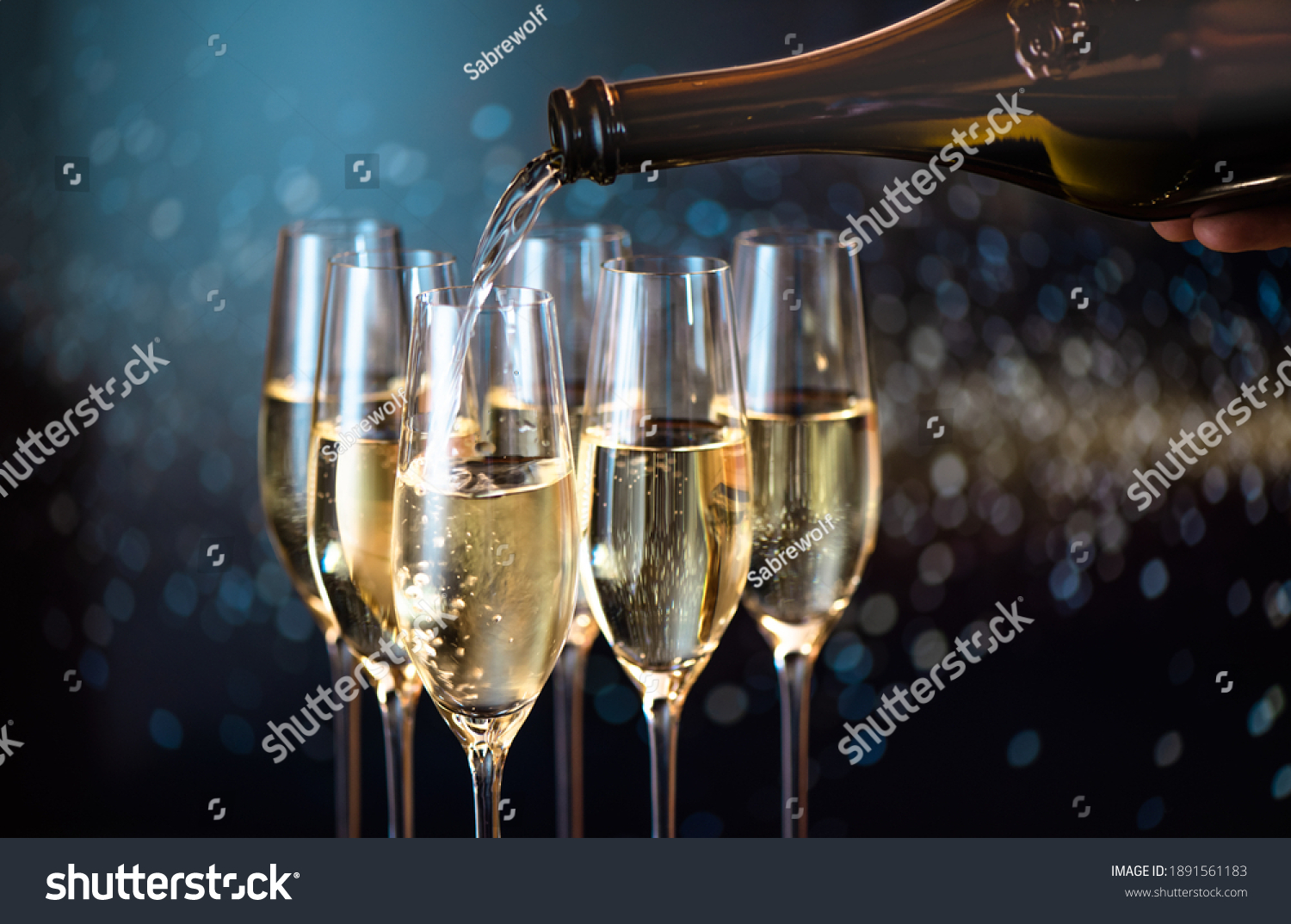 pouring champagne for a toast in a celebratory atmosphere with glasses of champagne  on golden flakes bokeh  background #1891561183