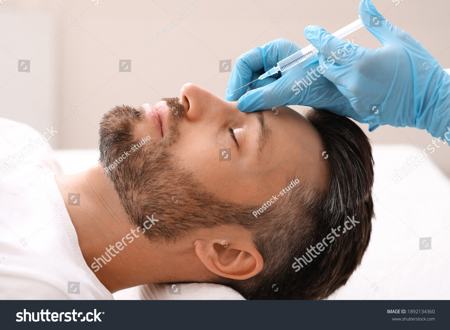 Side view of middle-aged man getting beauty injection in nose at aesthetic clinic. Plastic surgeon injecting anti-aging filler in handsome bearded man nose, having plastic correction, closeup #1892134360