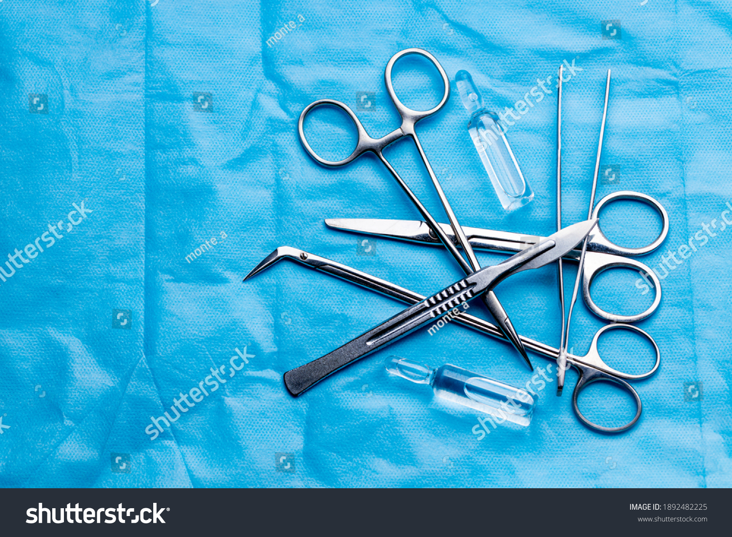 stack of surgical equipment at surgery desk. medical tools such scissors, scalpel, forceps, tweezers over blue background. surgery concept. #1892482225
