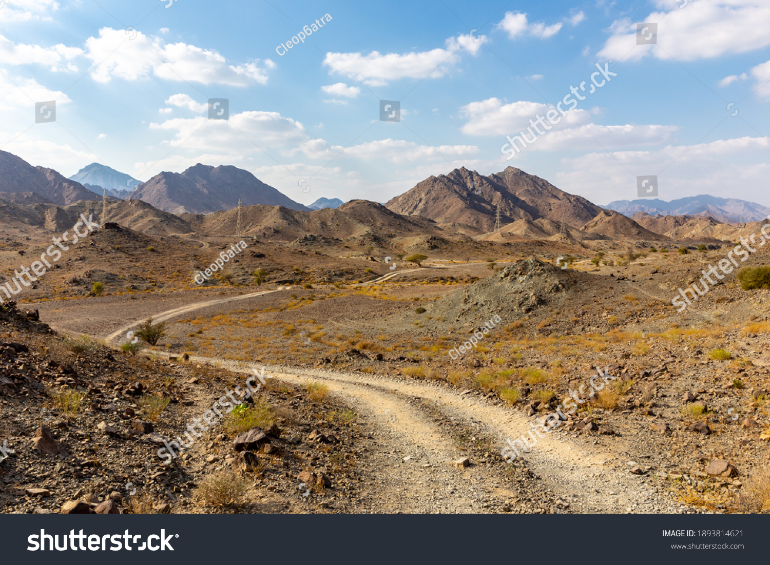 Copper Hike trail, winding gravel dirt road through Wadi Ghargur riverbed and rocky limestone Hajar Mountains in Hatta, United Arab Emirates.  #1893814621