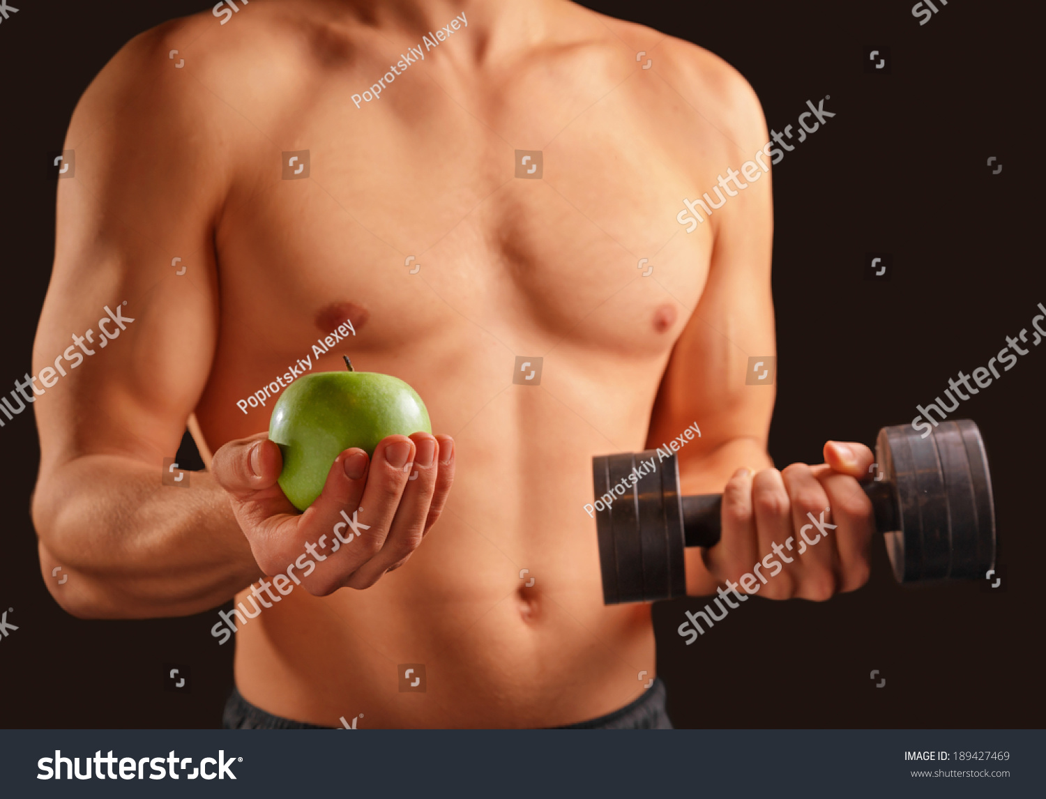 Unrecognizable man holds green apple and dumbbell, concept of healthy life #189427469
