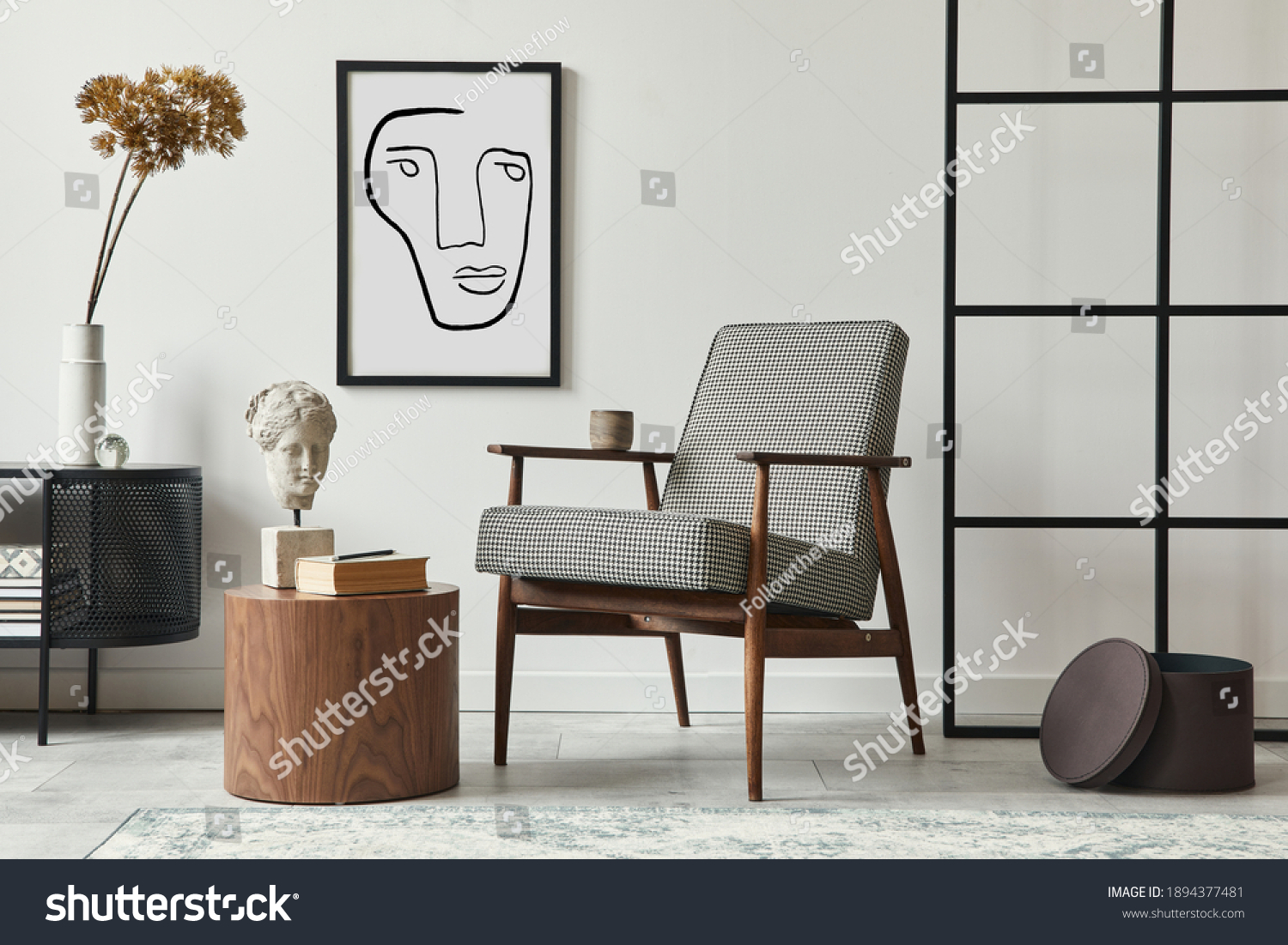 Stylish scandinavian composition of living room with design armchair, black mock up poster frame, commode, wooden stool, book, decoration, loft wall and personal accessories in modern home decor. #1894377481