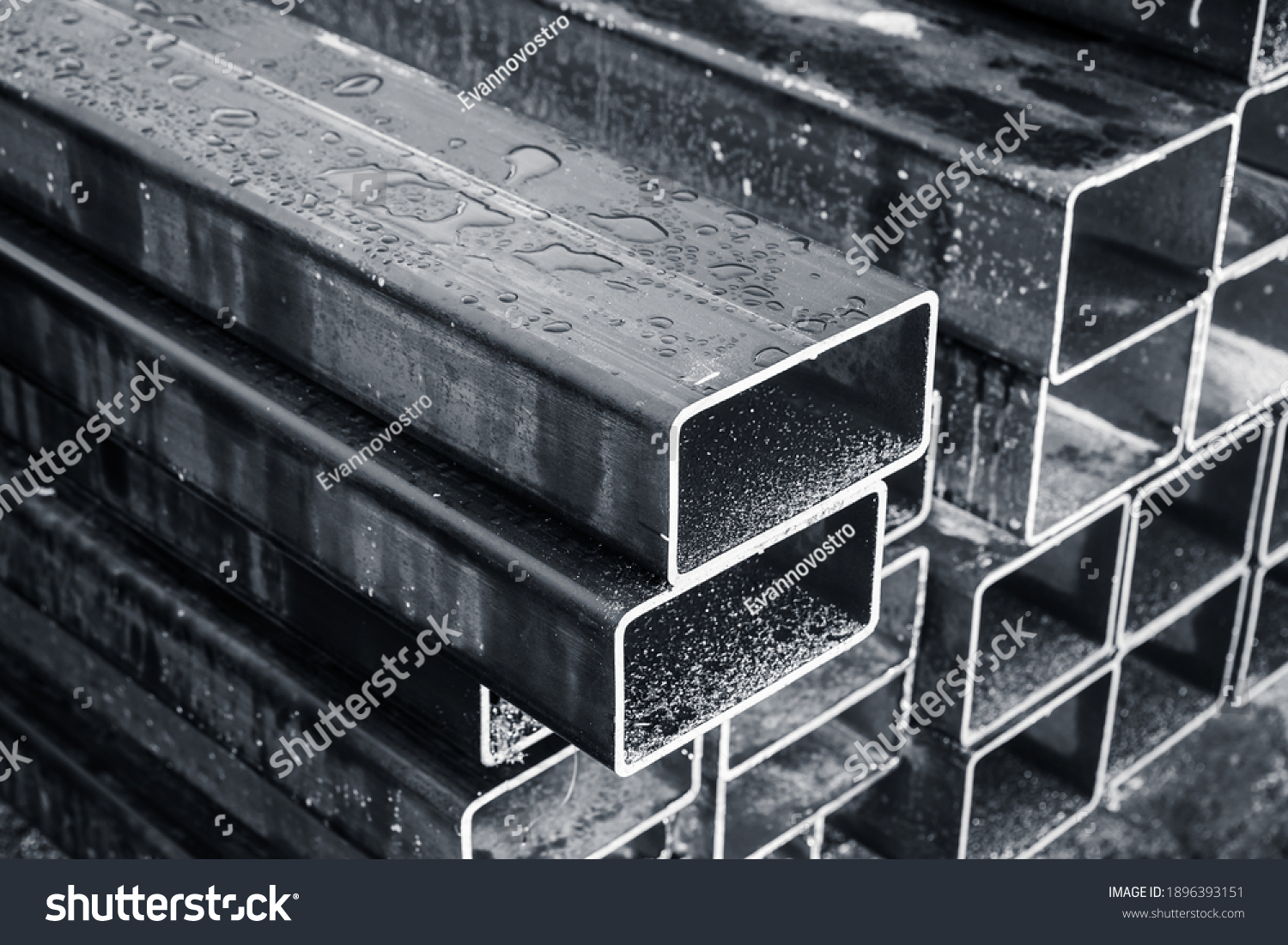 Stacked steel pipes with rectangular cross-section, close-up monochrome photo with selective focus #1896393151