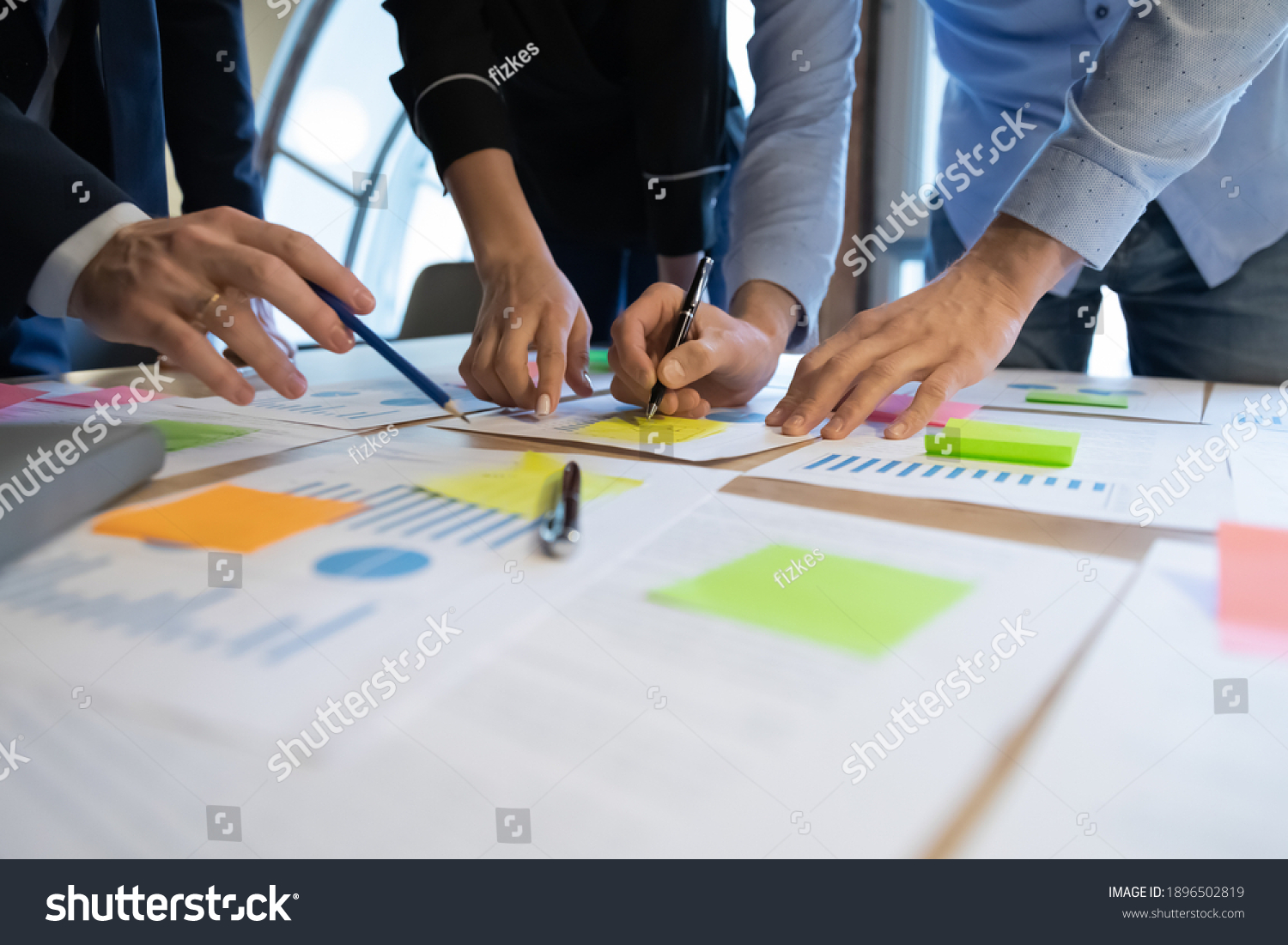 Close up diverse employees working on financial project statistics or report, writing notes on colorful sticky papers, checking documents, coworkers developing business strategy, teamwork #1896502819