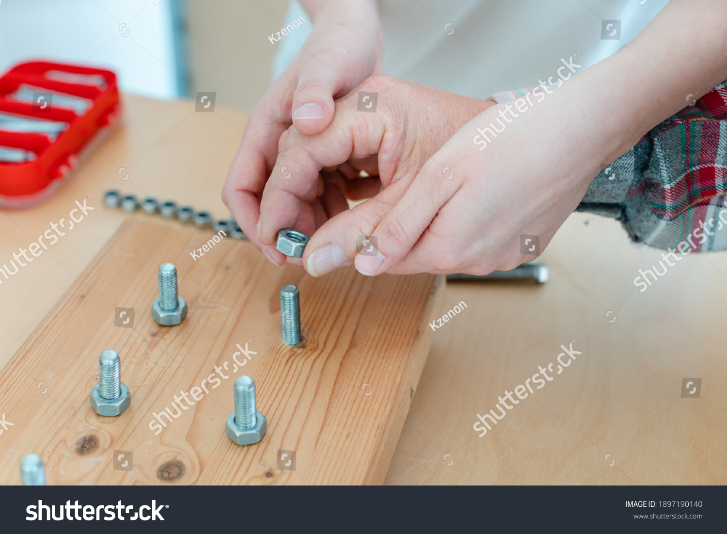 Closeup on hand of man in occupational therapy screwing nut on bolt #1897190140