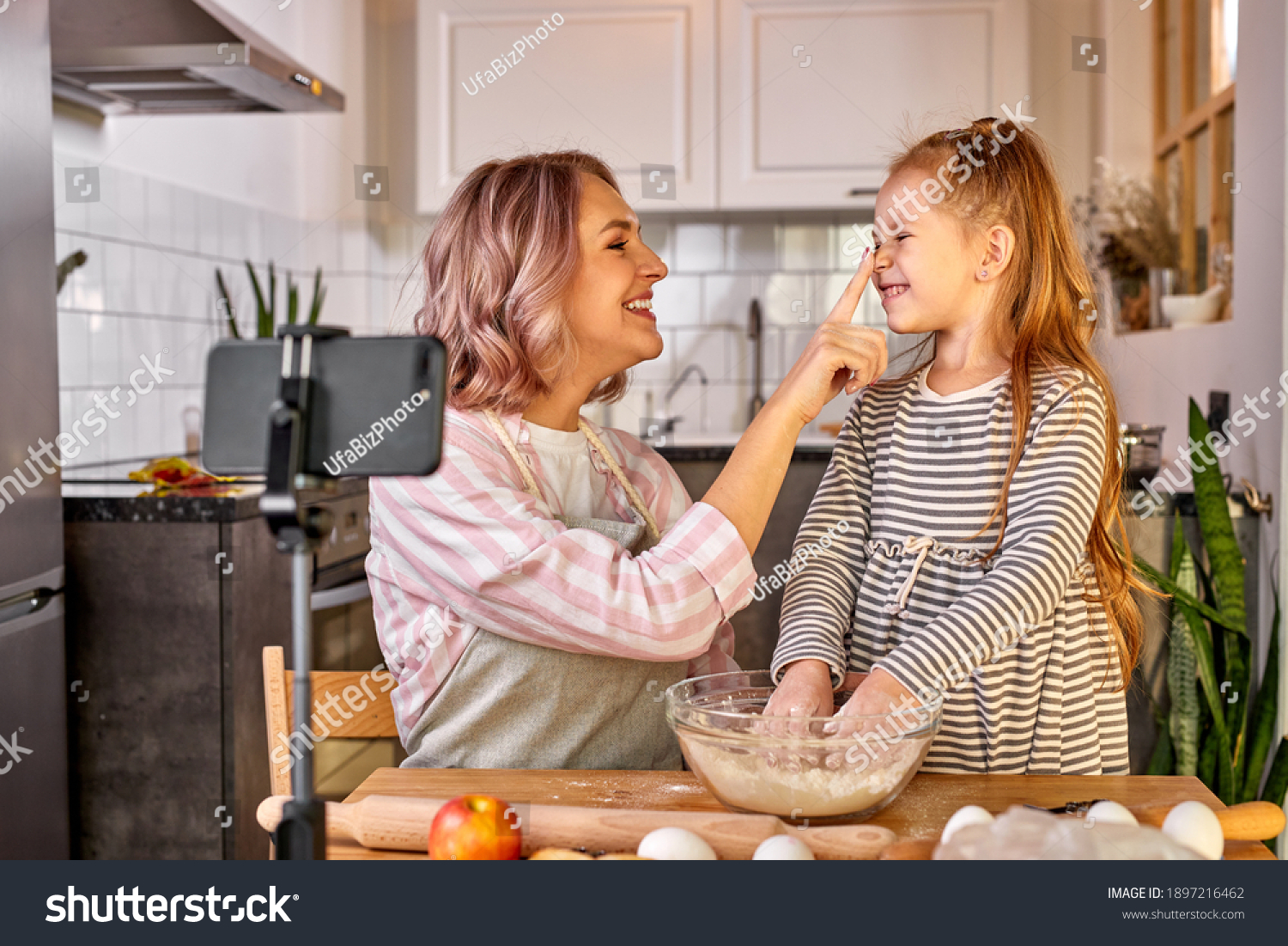 mother food blogger records the process of cooking with daughter on smartphone's camera, they have fun, talk, enjoy preparing food together #1897216462