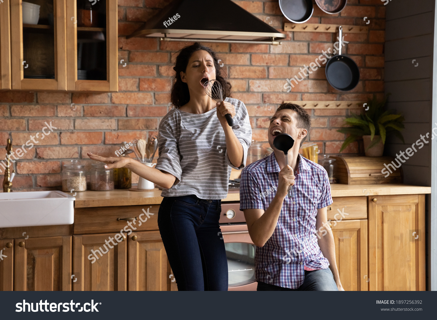 Overjoyed millennial Caucasian man and woman have fun dancing singing in modern kitchen at home. Excited happy young couple feel playful enjoy good morning in new own house or flat. Rental concept. #1897256392