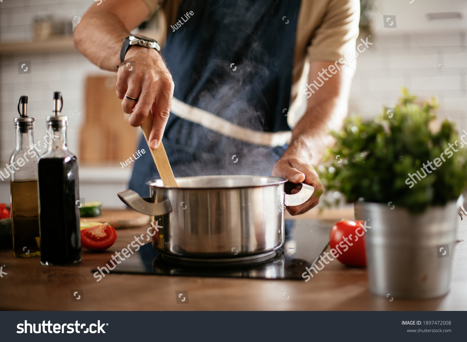 Young man cooking lunch at home. Handsome man preparing delicious food.  #1897472008