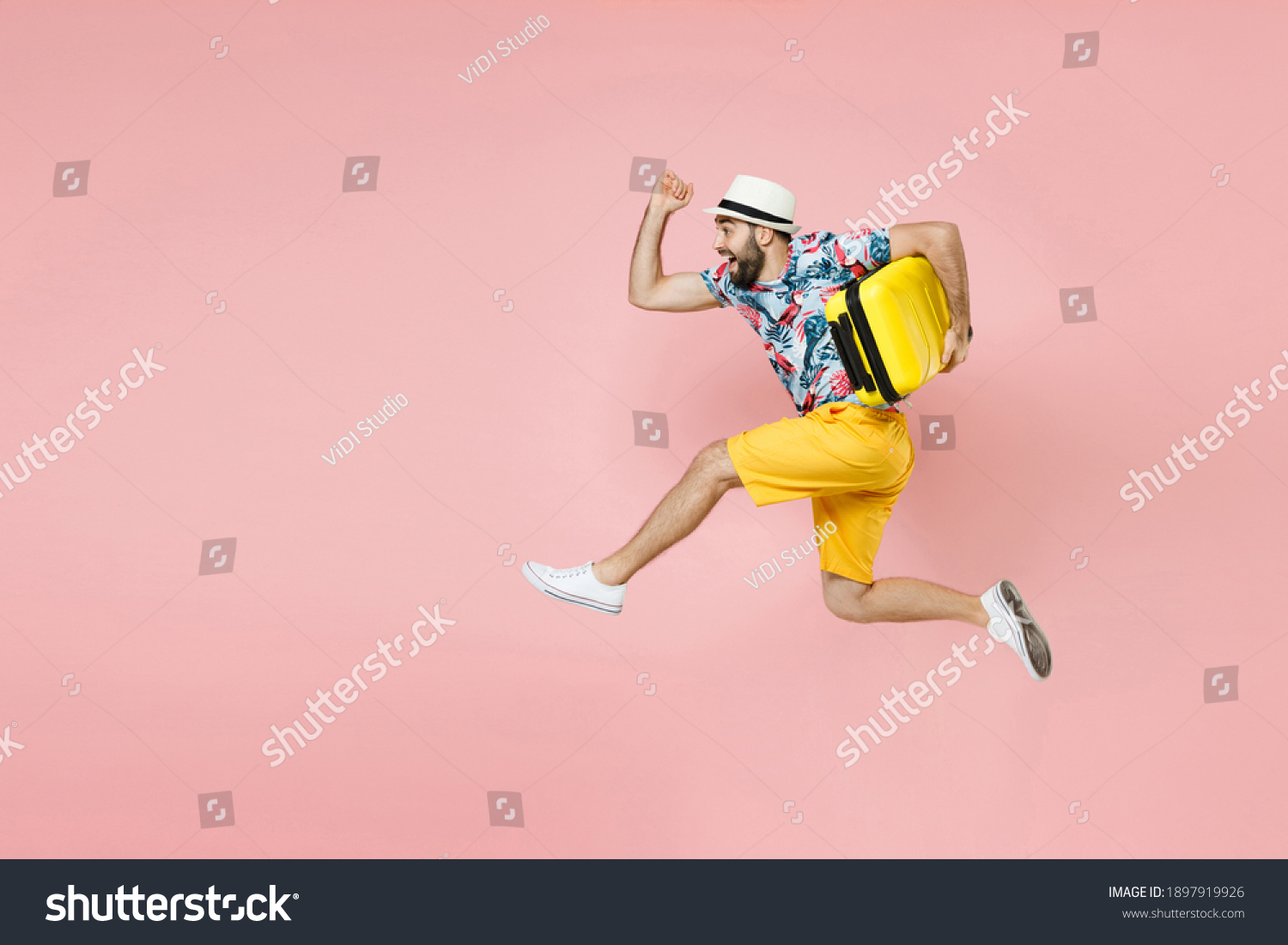 Full length side view of cheerful traveler tourist man in summer clothes hat jumping running hold suitcase isolated on pink background. Passenger traveling on weekend. Air flight journey concept #1897919926