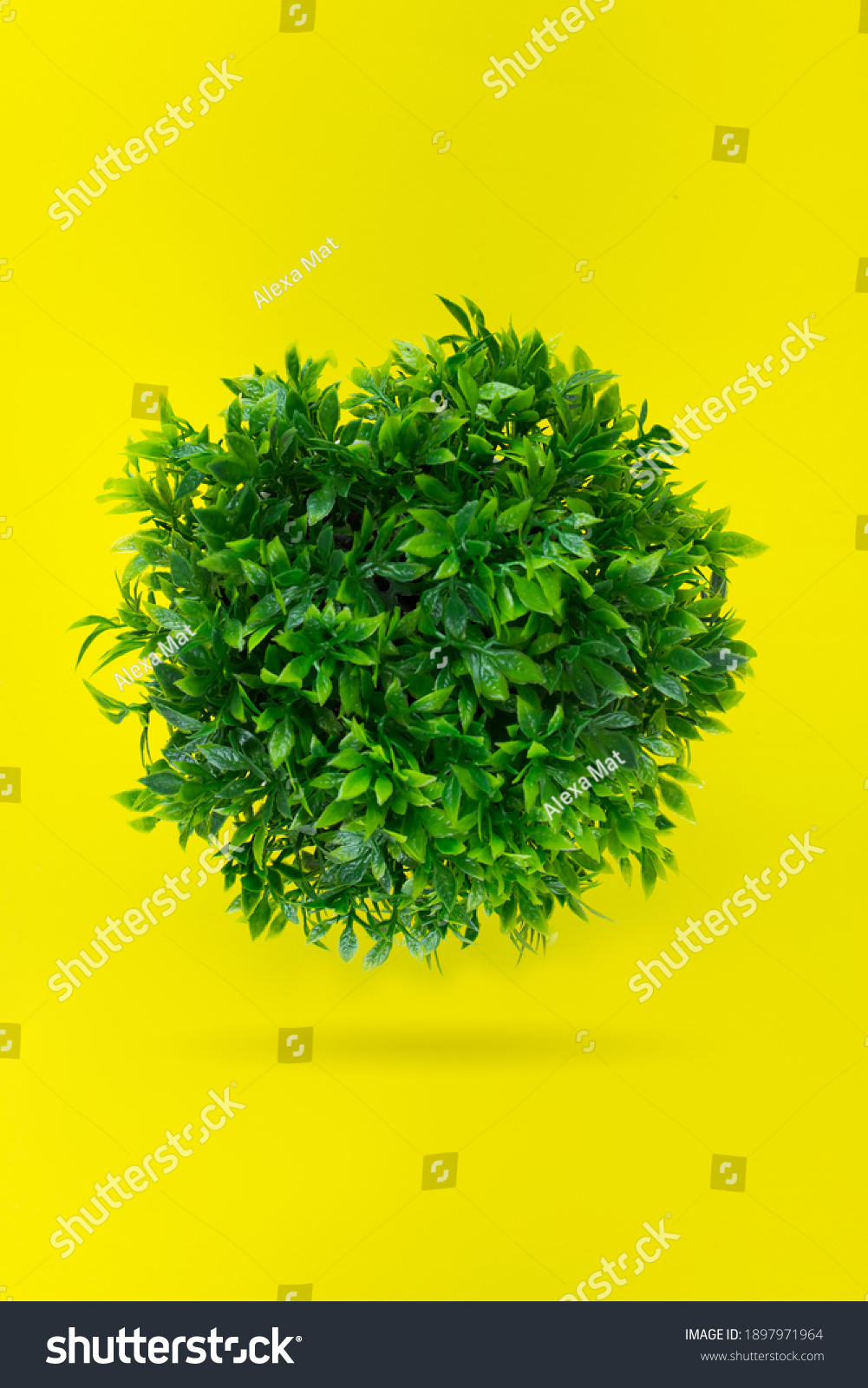 Green grassy ball, Leaf covered Earth on a yellow background. Concept day earth. Environmentally friendly planet #1897971964