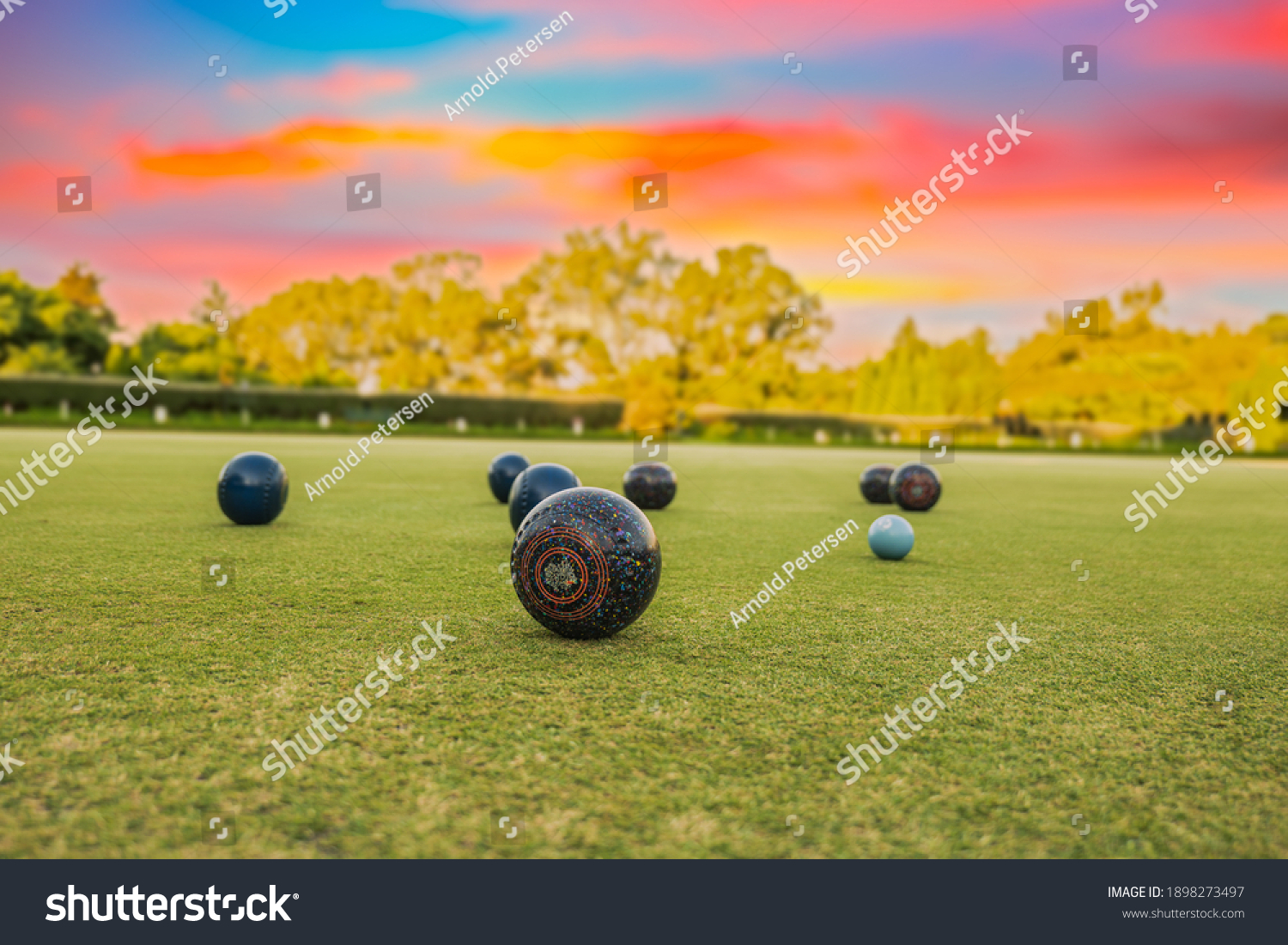 Lawn bowls balls in a field after the game with a colourful sunset #1898273497