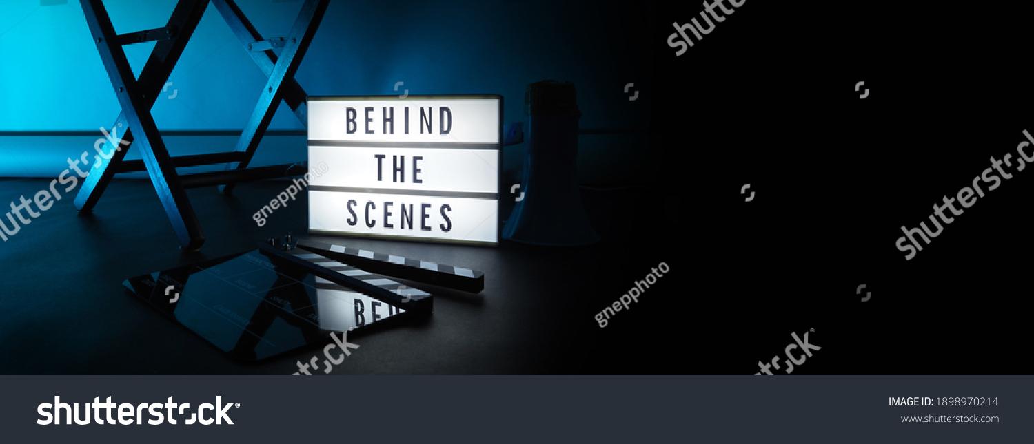 Behind the scenes letterboard text on Lightbox or Cinema Light box. Movie clapperboard megaphone and director chair beside. Background LED color change loop. static camera in video production studio. #1898970214