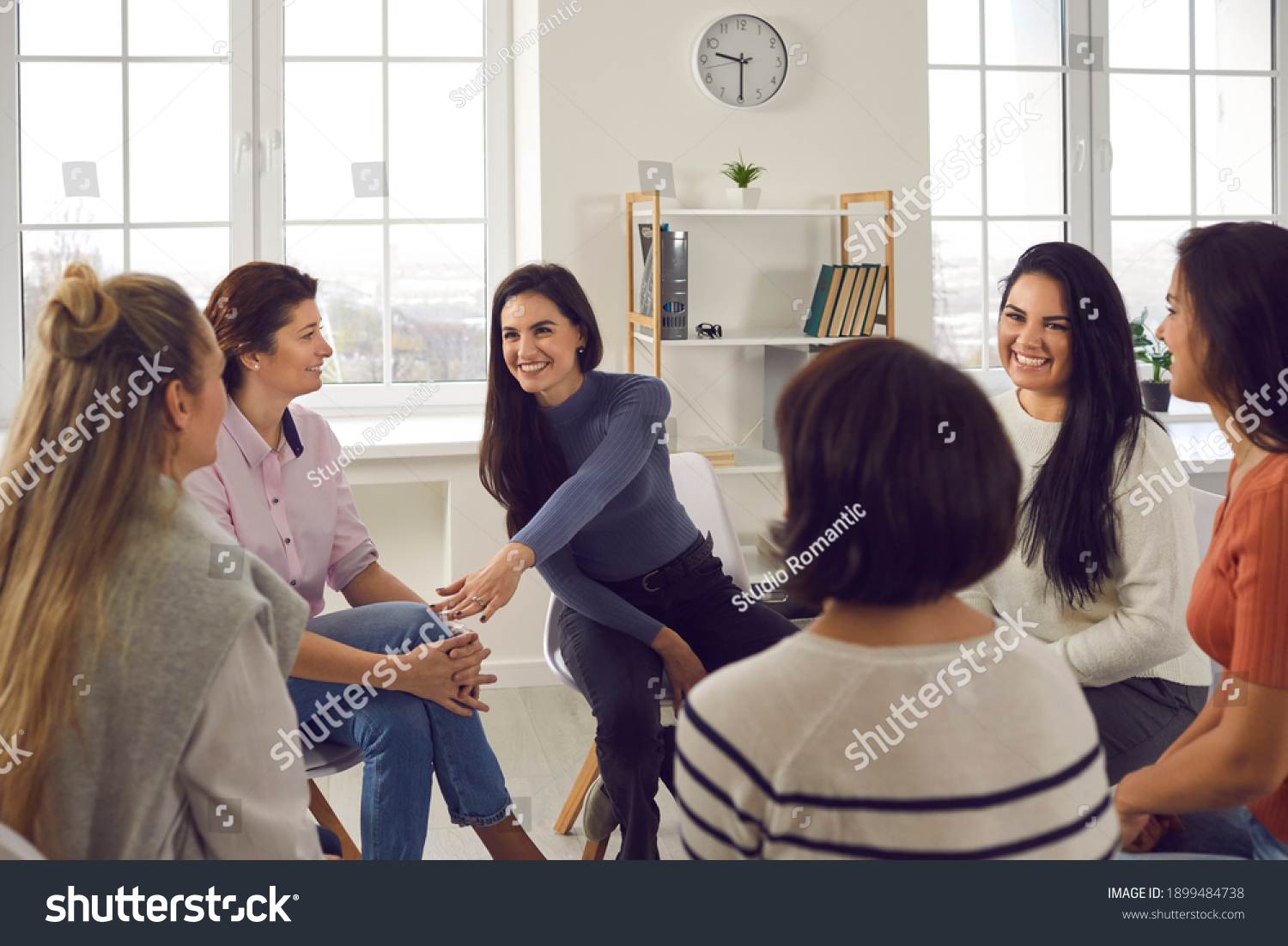 Happy positive smiling female coach, therapist or business team manager supporting and motivating young women in group therapy session or corporate staff training meeting at work #1899484738