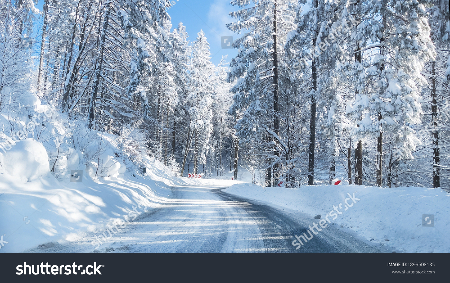 Snowy winter road in a mountain forest. Beautiful winter landscape. #1899508135
