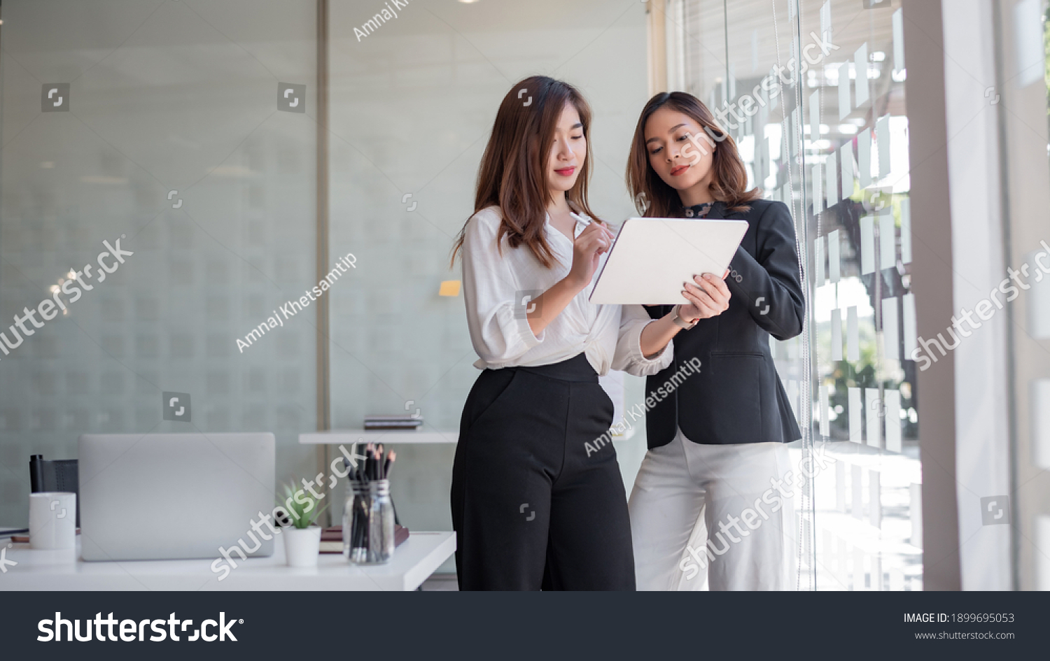 Two asian business woman work together to get the job done at the office. #1899695053