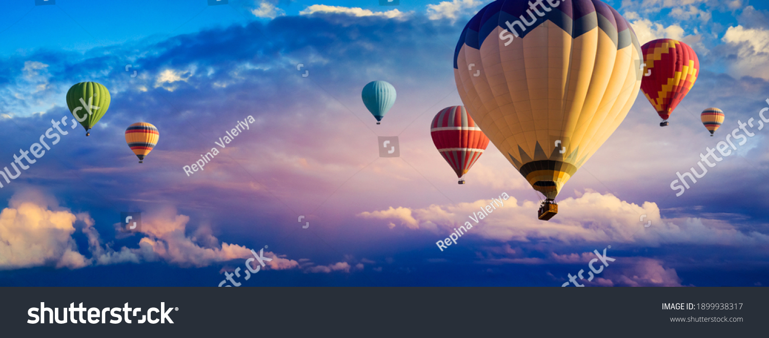Hot Air Balloon Ride at sunrise background for wide banner of travel agency or adventure tour. Morning hot-air balloon flight with beautiful clouds. Romance of ballooning in a good weather. #1899938317