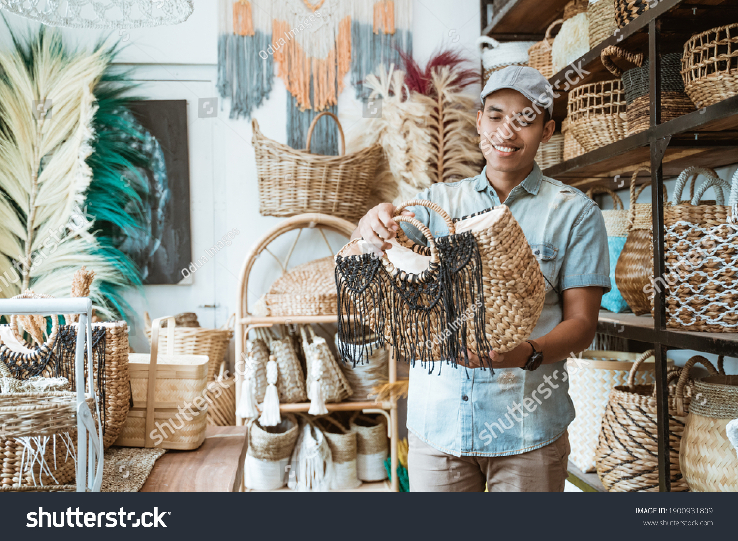 man in the hat holds and looks at the woven bag at the craft shop #1900931809
