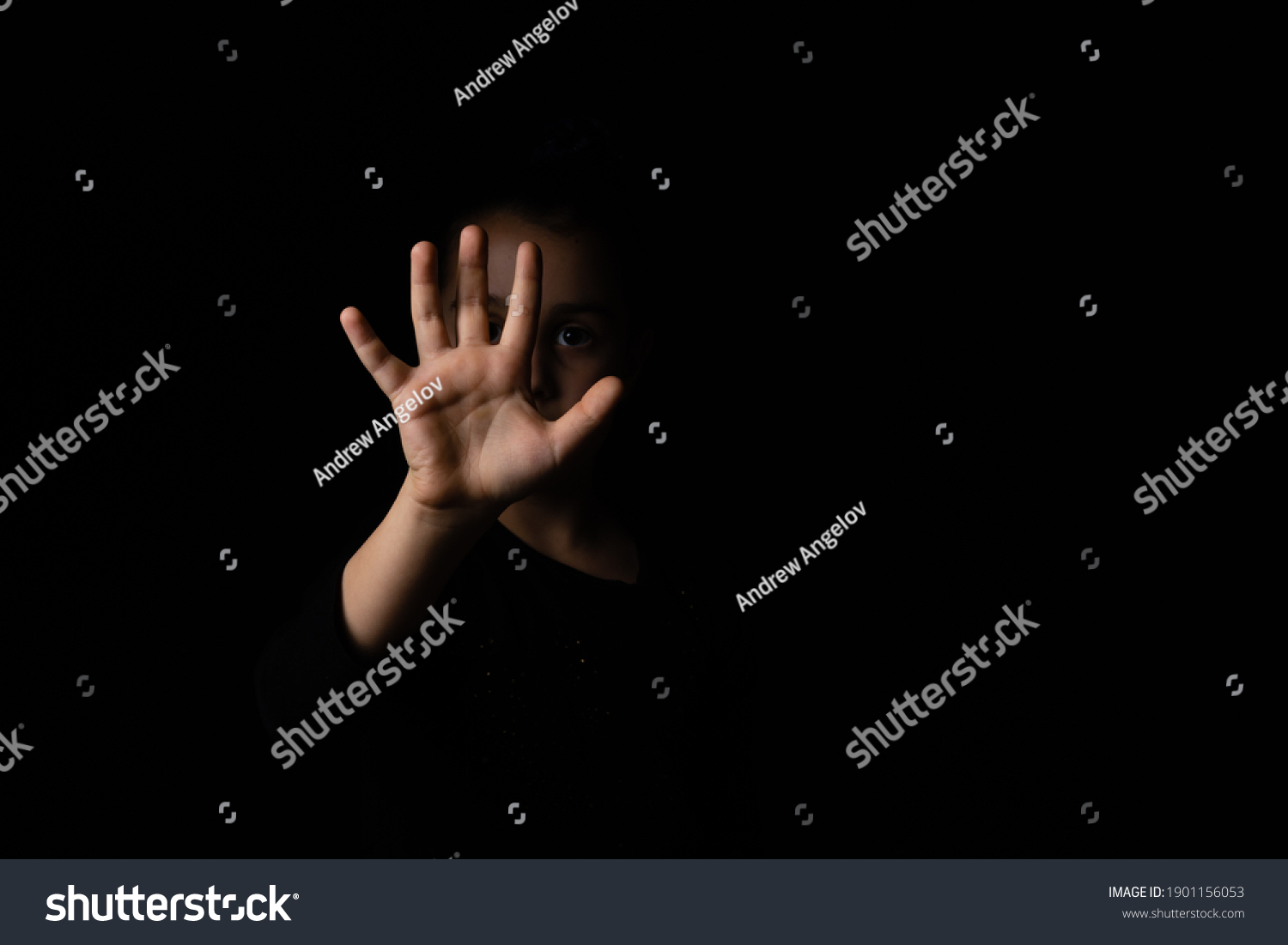 little girl with a raised hand making a stop sign gesture on a black background. Violence, harassment and child abuse prevention concept. #1901156053