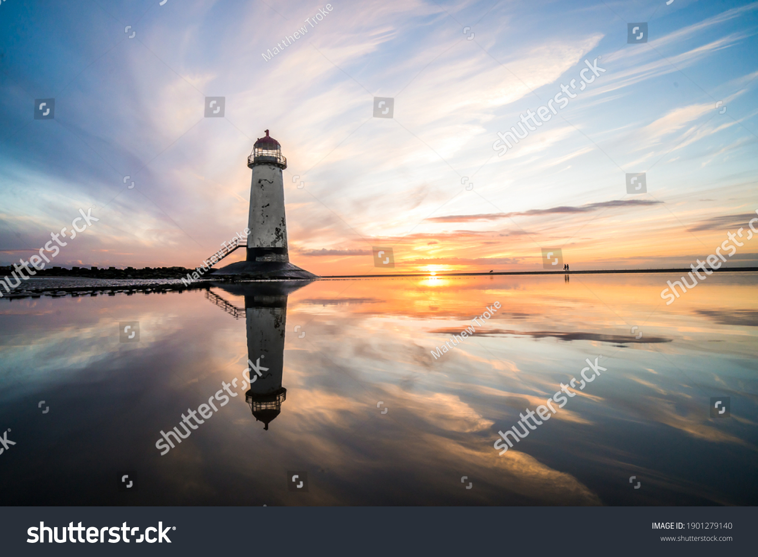 Lighthouse standing in pool of water stunning sunset sunrise reflection reflected in water and sea steps up to building north Wales seashore sand beach still water orange glow golden hour blue hour #1901279140