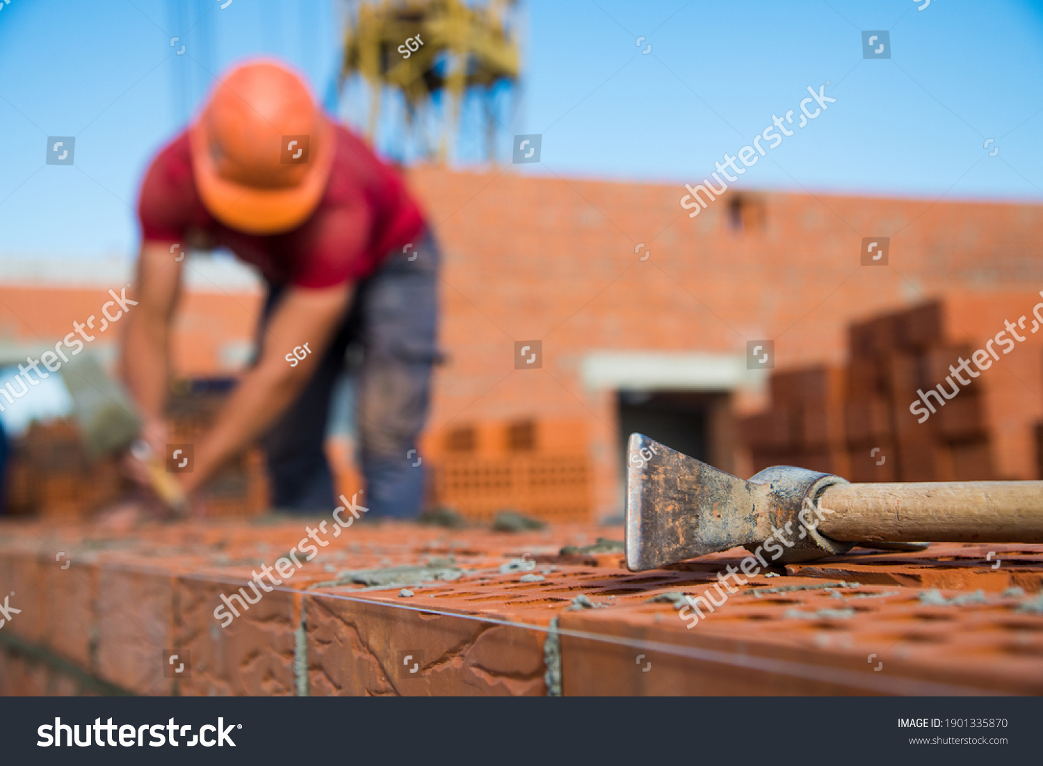 Bricklayer worker installing brick masonry on exterior wall. Professional construction worker laying bricks. #1901335870
