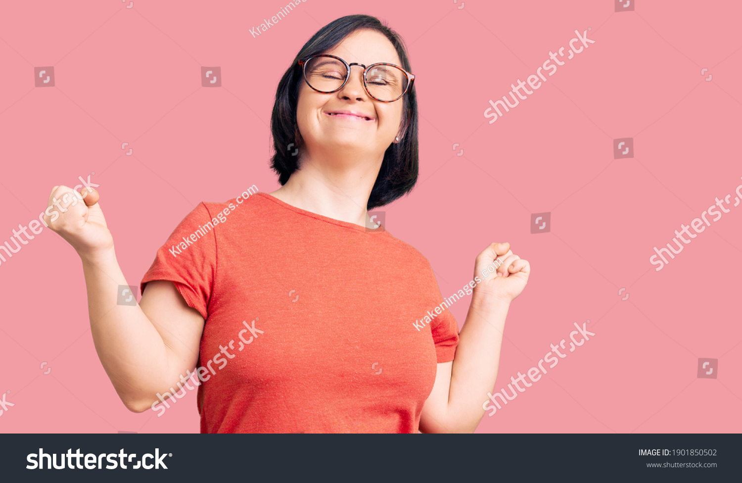 Brunette woman with down syndrome wearing casual clothes and glasses very happy and excited doing winner gesture with arms raised, smiling and screaming for success. celebration concept.  #1901850502