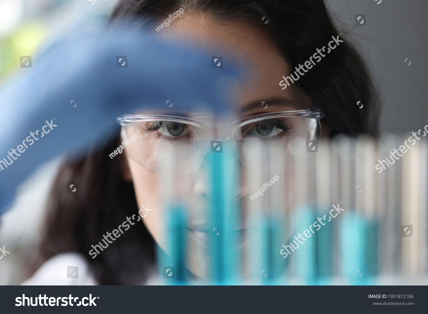 Portrait of woman in glasses who looks at test tubes with liquid. Research and development concept #1901872186