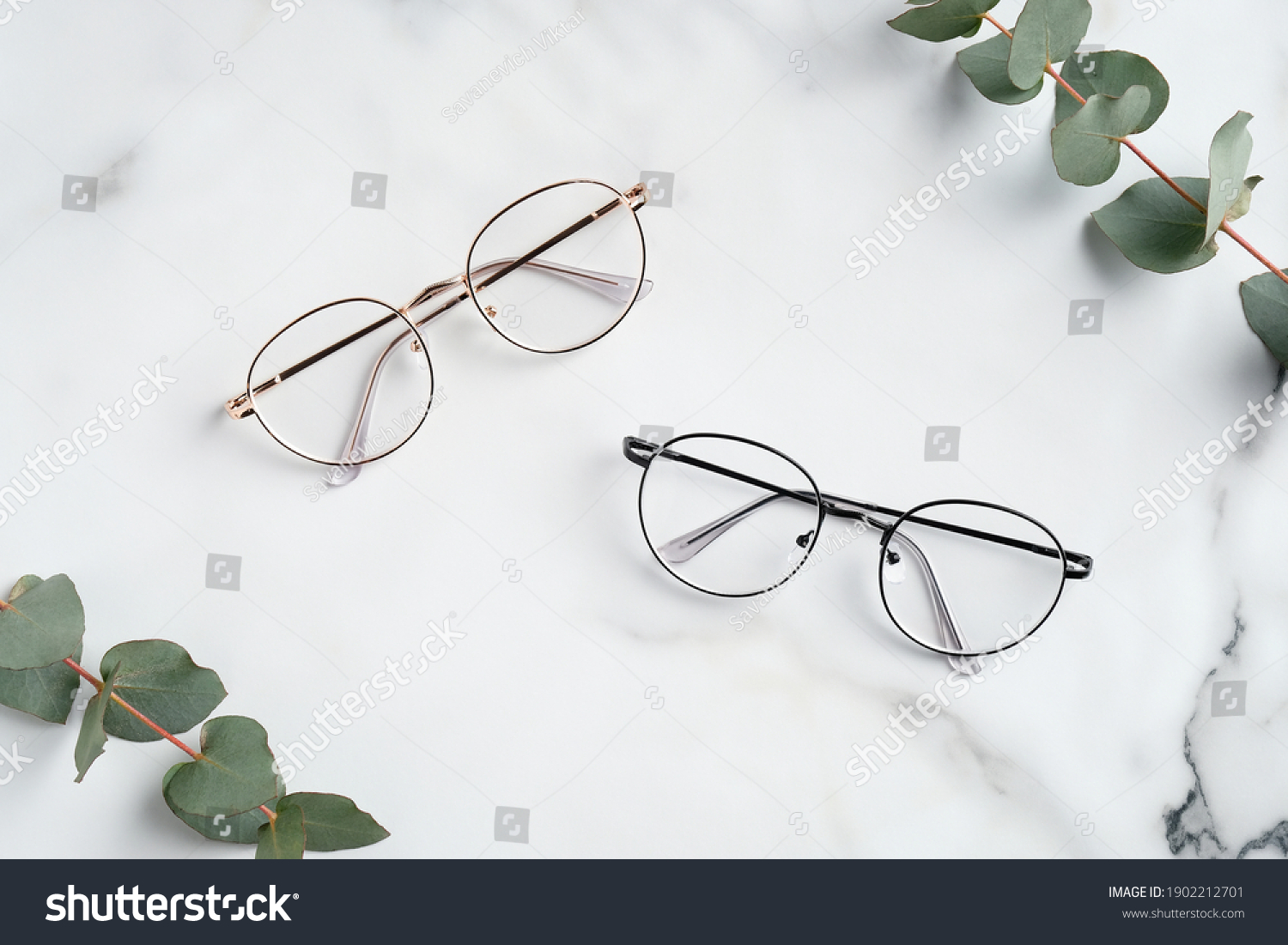 Women's glasses and eucalyptus leaves on marble table top view.  #1902212701