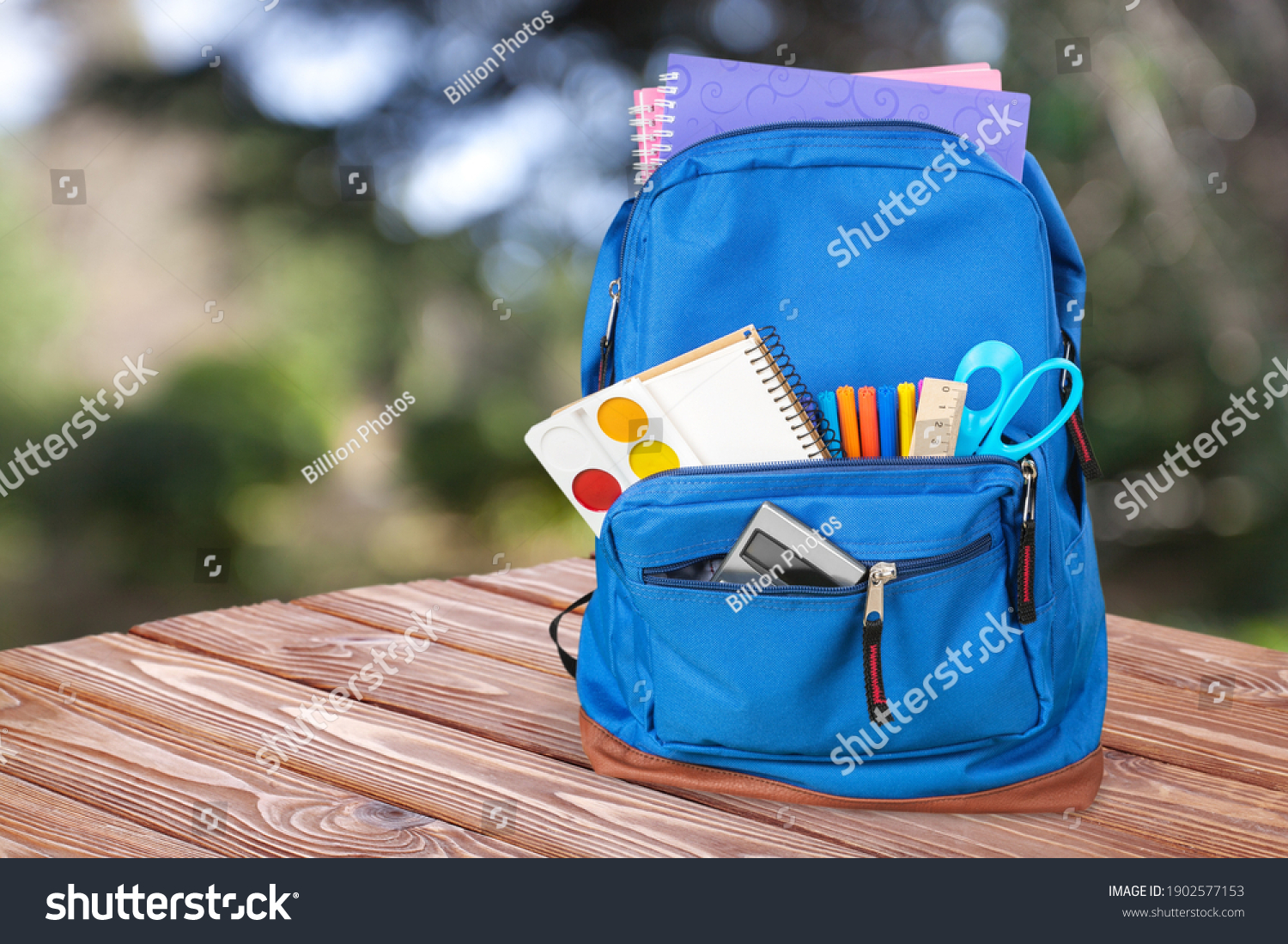 Classic school backpack with colorful school supplies and books on desk. #1902577153