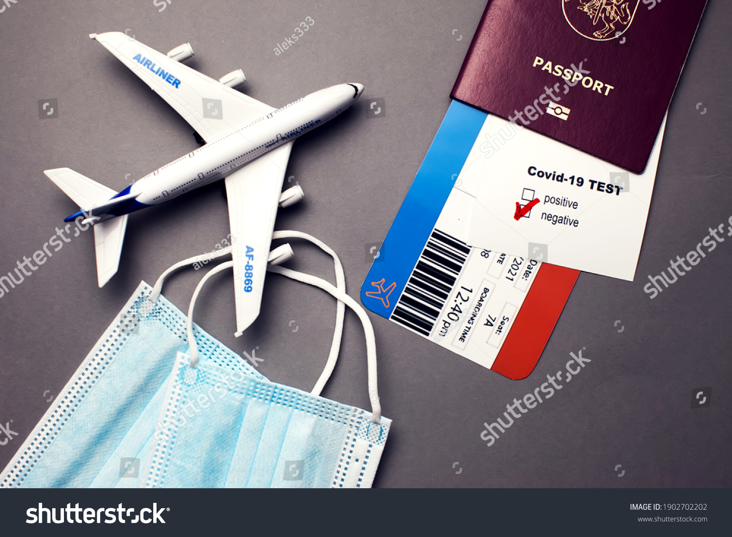 Traveling during COVID-19 pandemic, passport with airline ticket, covid-19 negative test, medical masks and plane on grey background, airport security health and safety check concept #1902702202