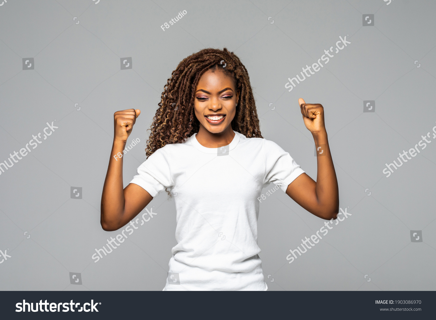 Overjoyed young african american woman screaming with joy celebrating victory win success on white background, happy excited black girl rejoicing triumph feeling winner #1903086970