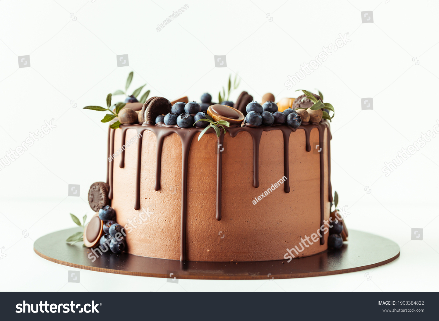 Chocolate cake decorated with blueberries, cookies and chocolates on a white background. Flat lay of the brown birthday cake #1903384822