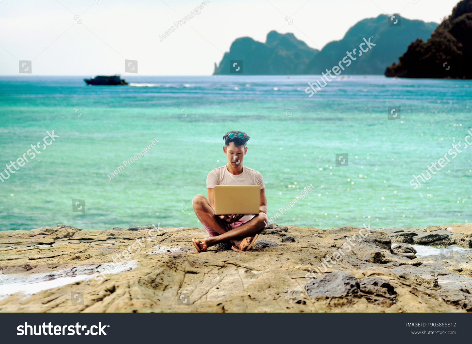 a digital nomad asian man working by the tropical sea with his laptop #1903865812