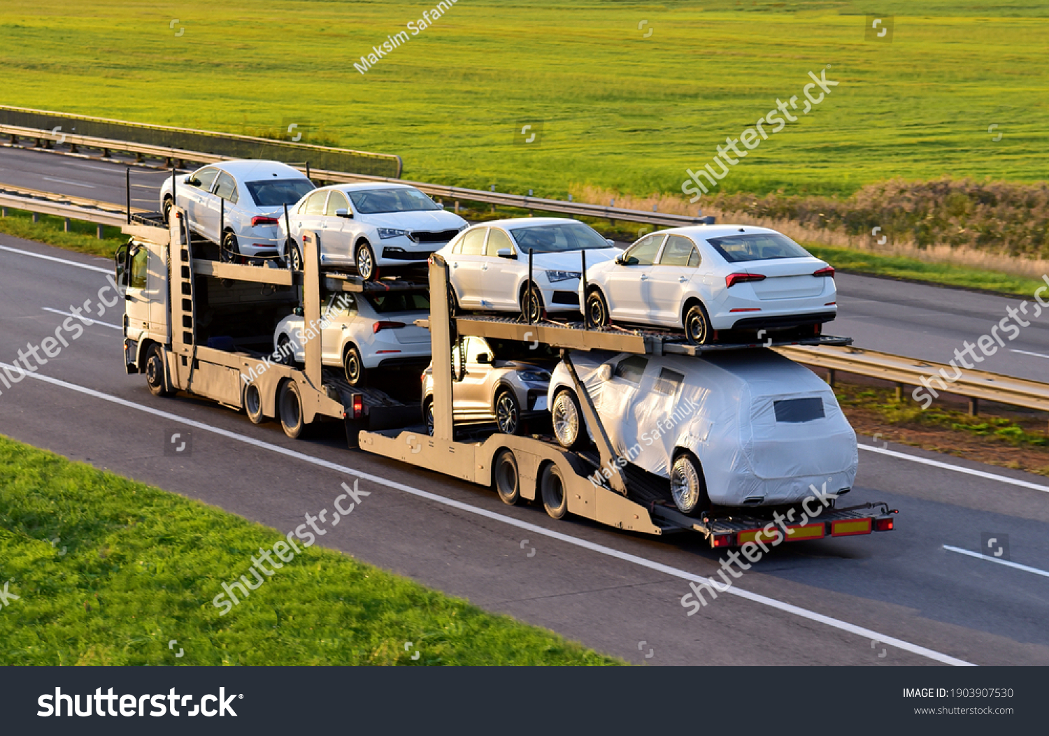 Car carrier trailer transports cars on highway on sunset background. Auto transport and car shipping services concept. Truck with Semi-remorque. Cars Shipping. Car transportation #1903907530