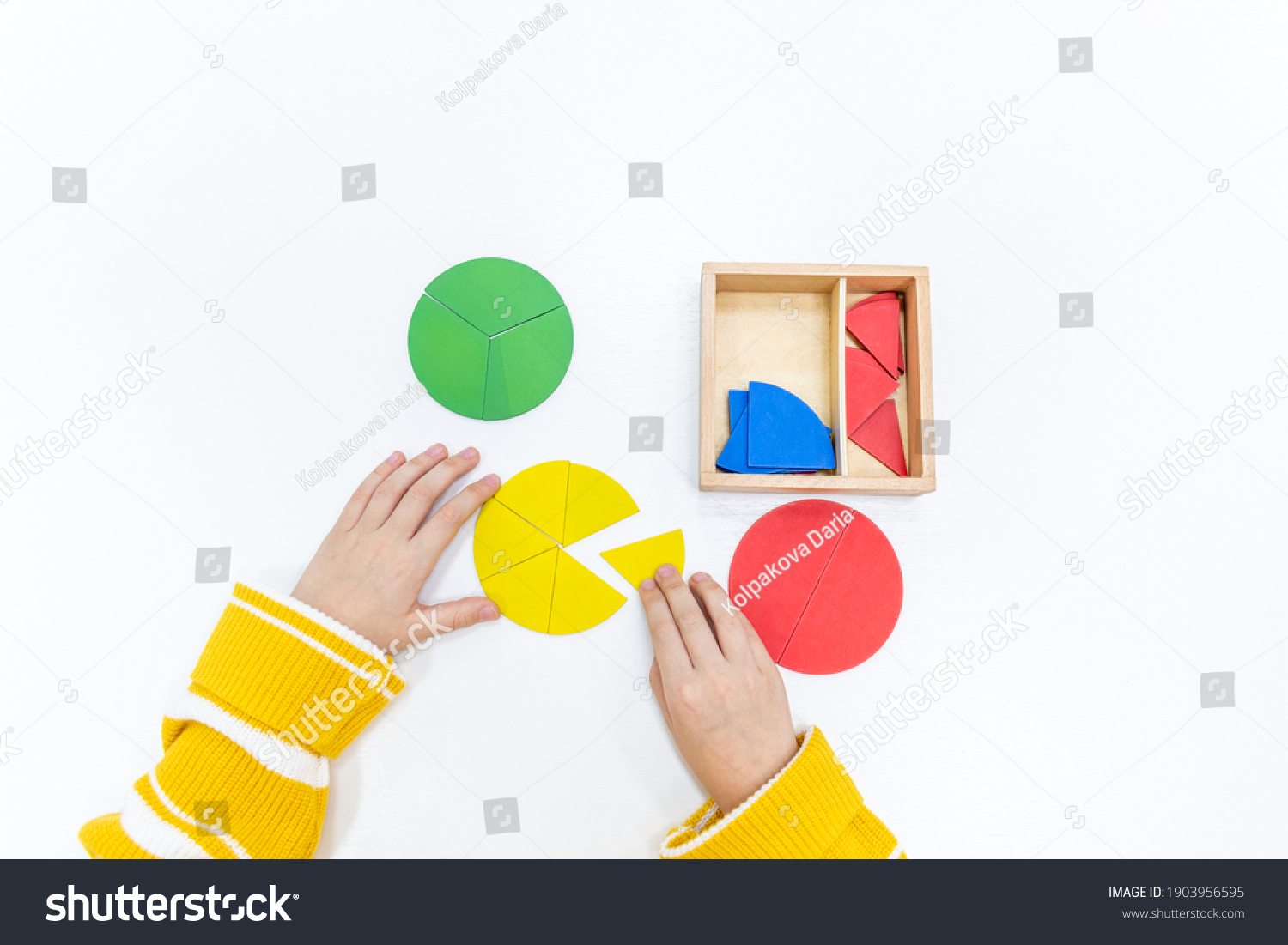 Top view of girls hand is playing and sorting a puzzle of colored wooden geometric shapes in montessori school. Concept of using a mathematical geometry learning resources for children education. #1903956595