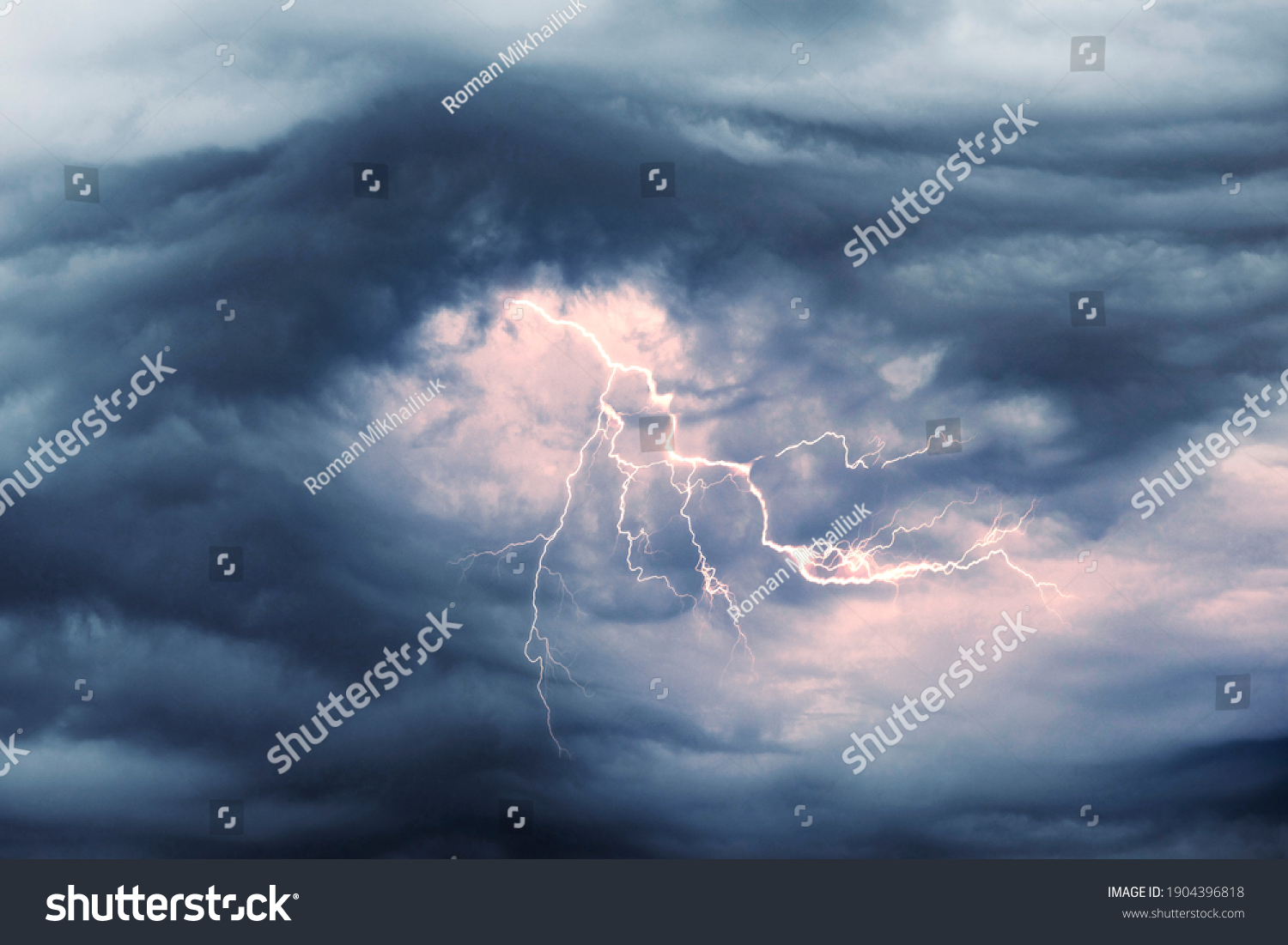 A terrible dangerous storm with a strong wind swirls thunderclouds in the mountains with fabulous twists, from which rain and hail or a thunderstorm with lightning flies. #1904396818