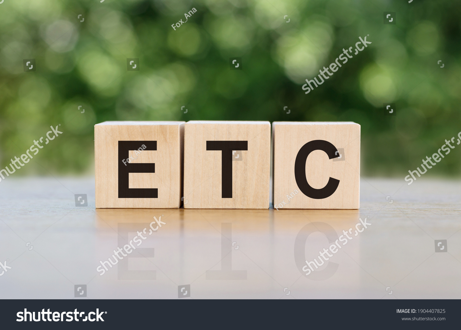 ETC (abbreviation of et cetera) word written on wooden blocks. The text is written in black letters and is reflected in the mirror surface of the table. #1904407825