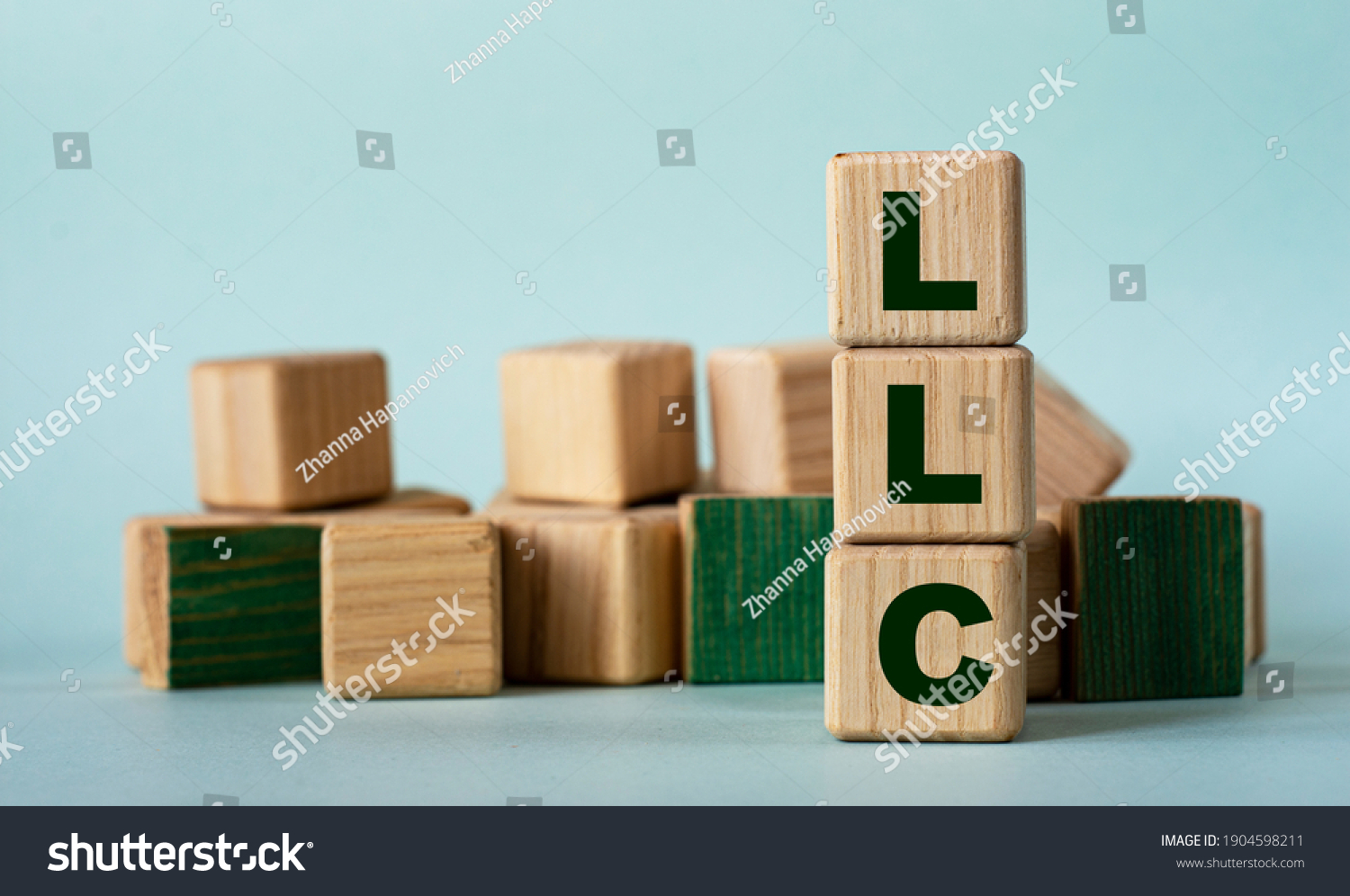 LLC (Limited Liability Company) - acronym on wooden cubes on a background of colored block on a light background. Business concept #1904598211