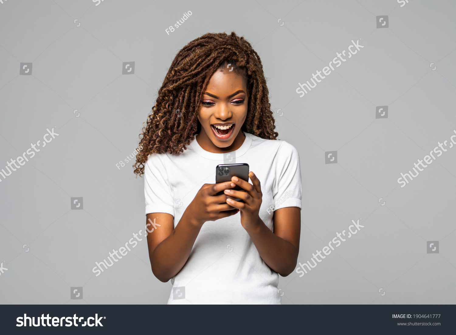 Excited woman texting on her phone isolated over white background #1904641777