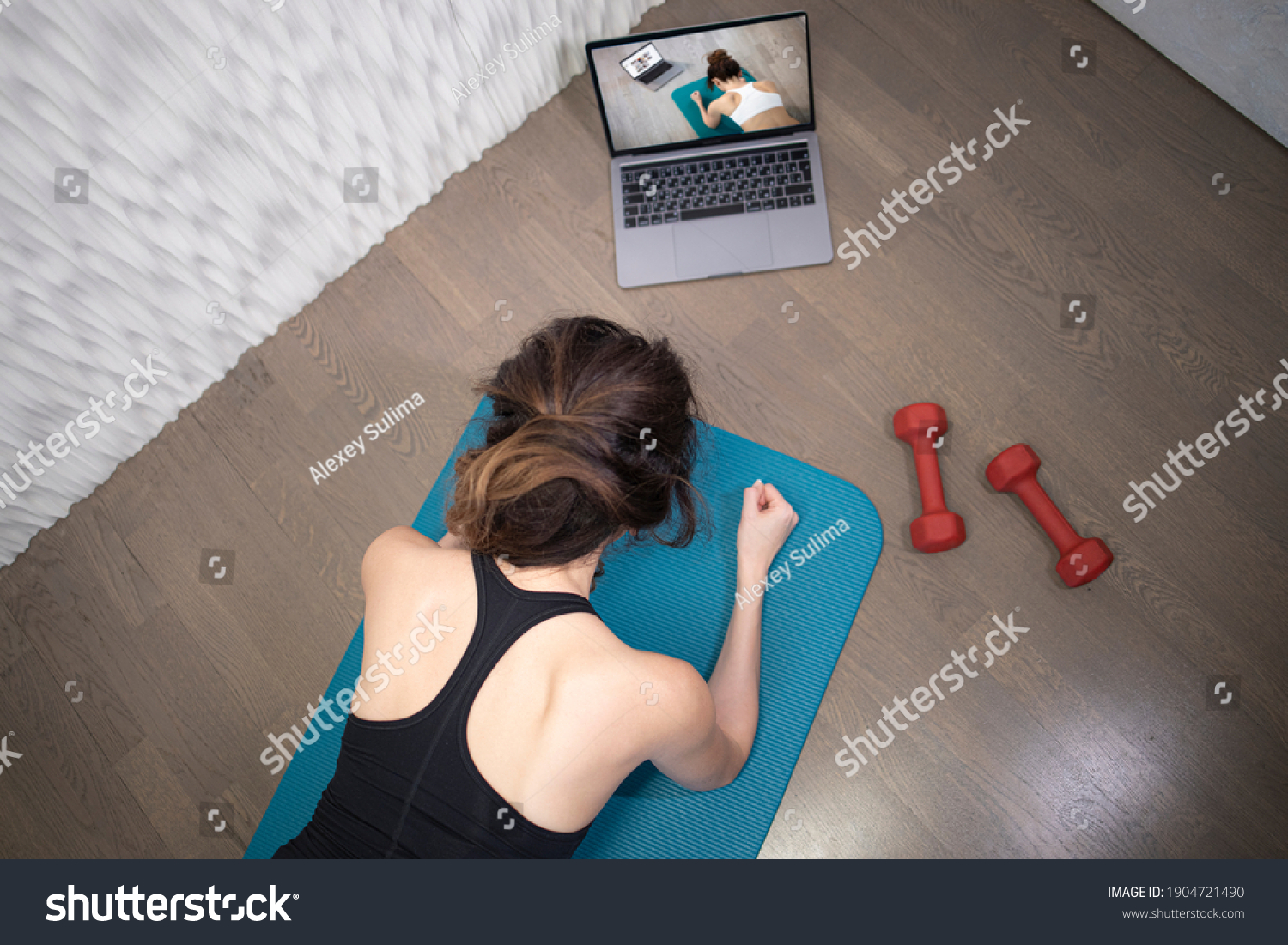 Young sporty slim woman has internet video online fitness training instructor modern laptop screen. Healthy lifestyle concept, online fitness and sport lessons. Plank exercise #1904721490