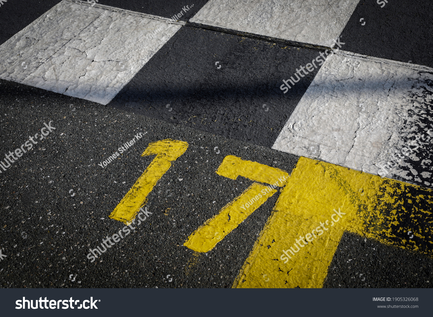 Grey asphalt road, yellow painted number seventeen on grey street, yellow lines like a corner on the road, space for text 
 #1905326068