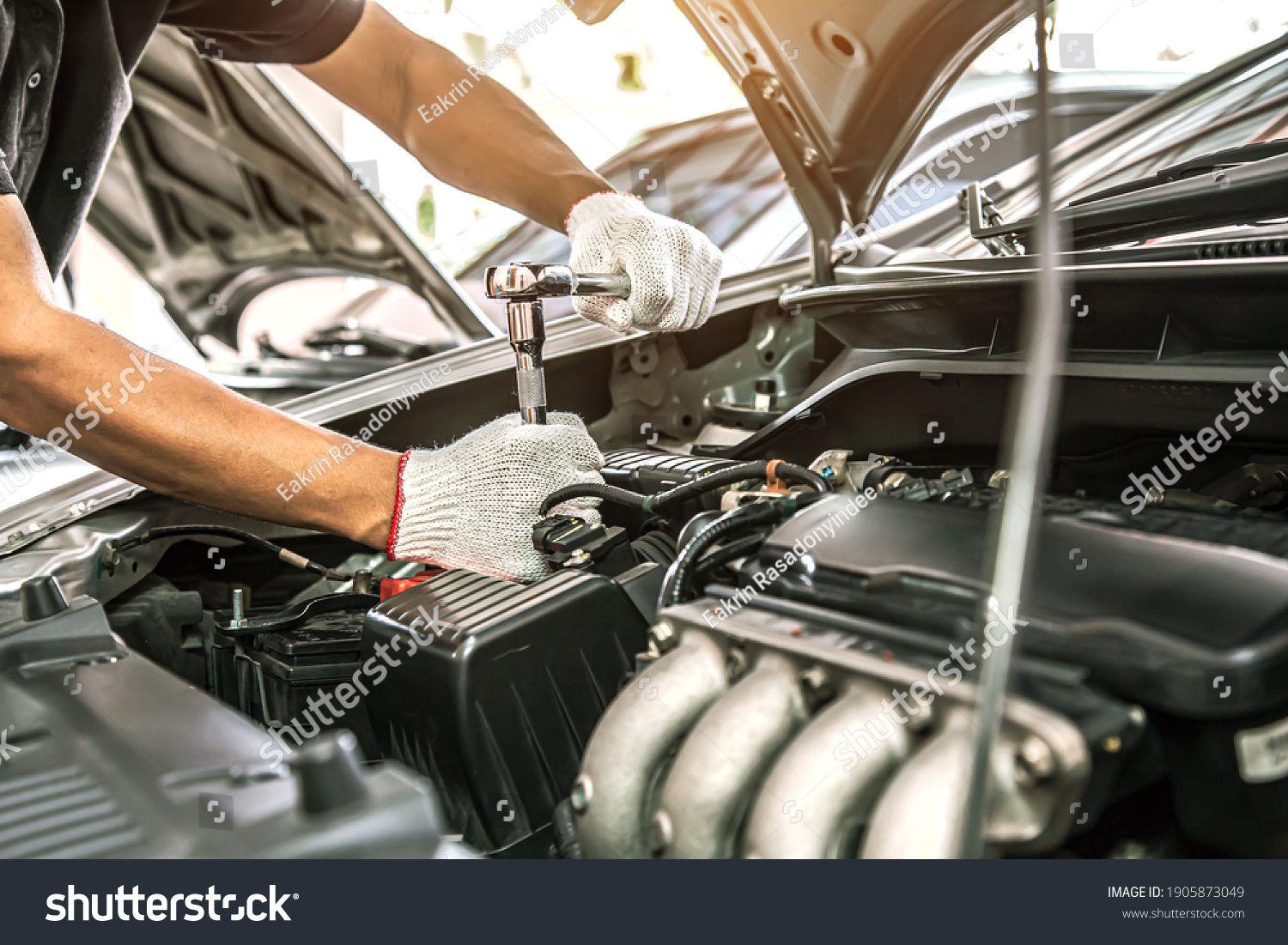 Close-up hands of auto mechanic are using the wrench to repair and maintenance auto engine is problems at car repair shop. Concepts of car care check and fixed and services insurance. #1905873049
