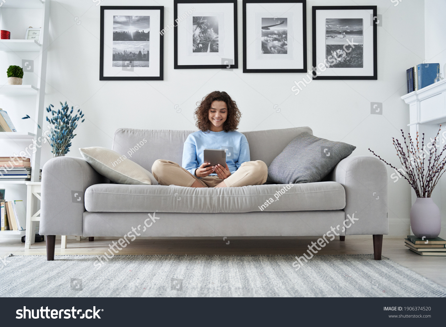 Happy hispanic teen girl holding pad computer gadget using digital tablet technology sitting on couch at home. Smiling young woman using apps, shopping online, reading news, browsing internet on sofa. #1906374520
