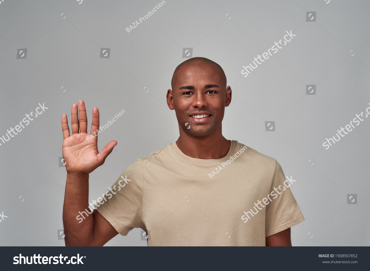 Glad man putting his right hand up in the air with an open palm and smiling #1908907852
