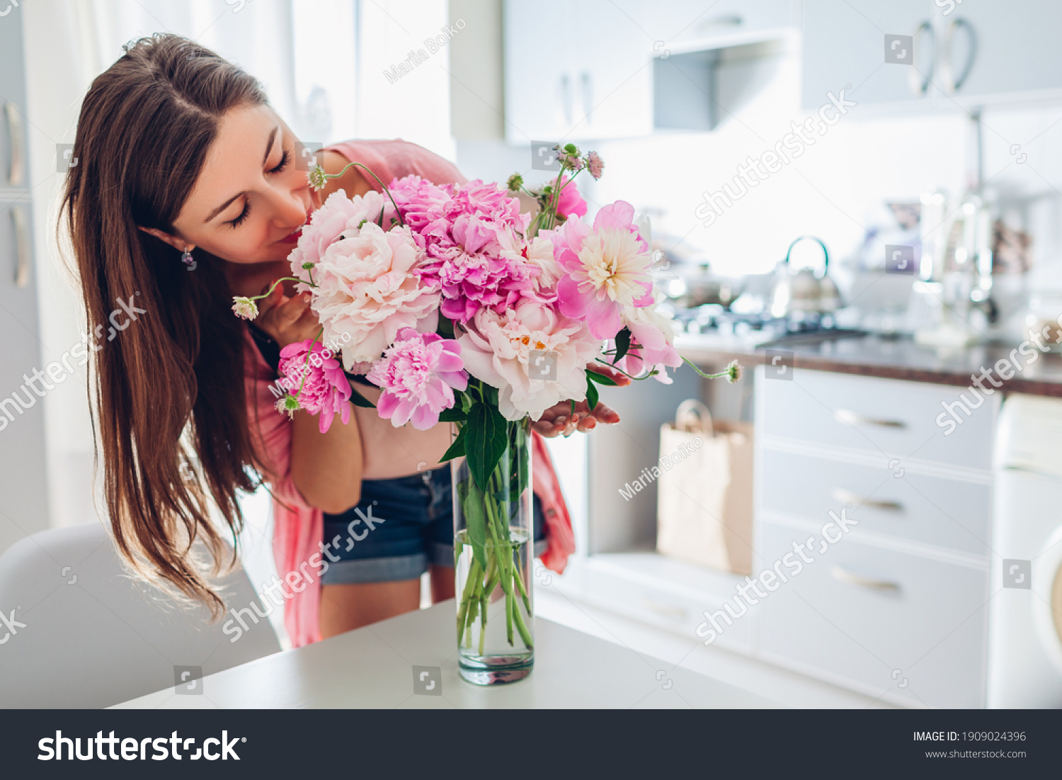 Valentine's day. Woman smelling bouquet of peonies at home. Housewife received present for holiday. Allergy free #1909024396