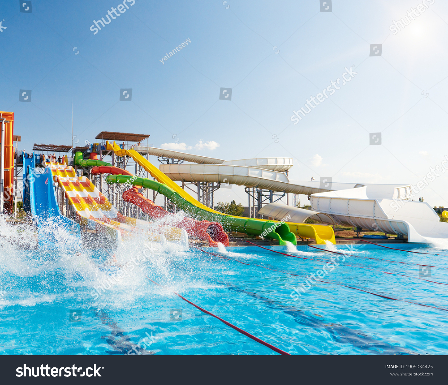 Water park, bright multi-colored slides with a pool. A water park without people on a summer day. #1909034425